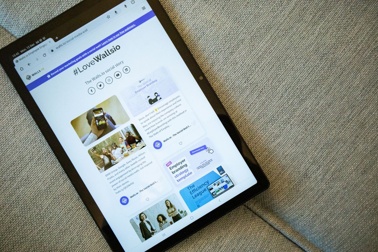 A tablet resting on a sofa displaying the Wallis.io website interface.